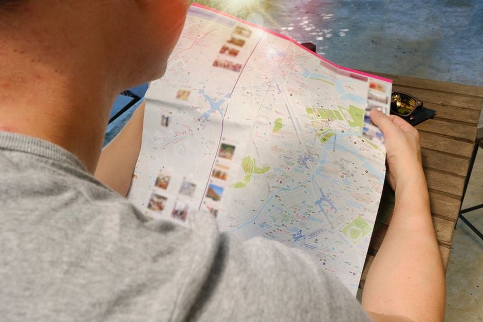 Traveller reading a folded paper map outdoors.