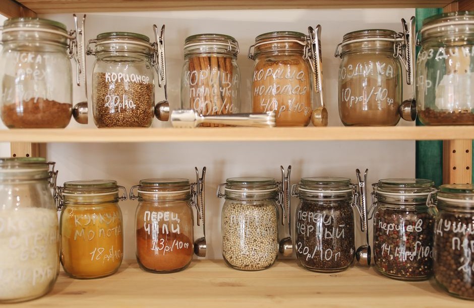 Glass jars of grains, spices and pantry ingredients on wooden shelves.