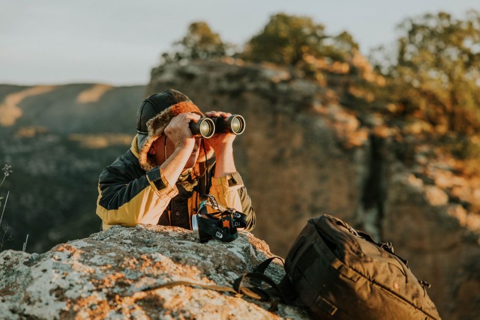 Photographer looking through a camera from a rocky viewpoint.